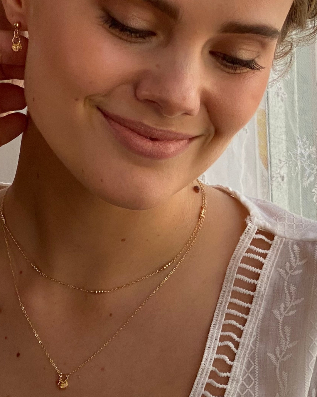 Close-up of a woman wearing a gold necklace with a small pendant.