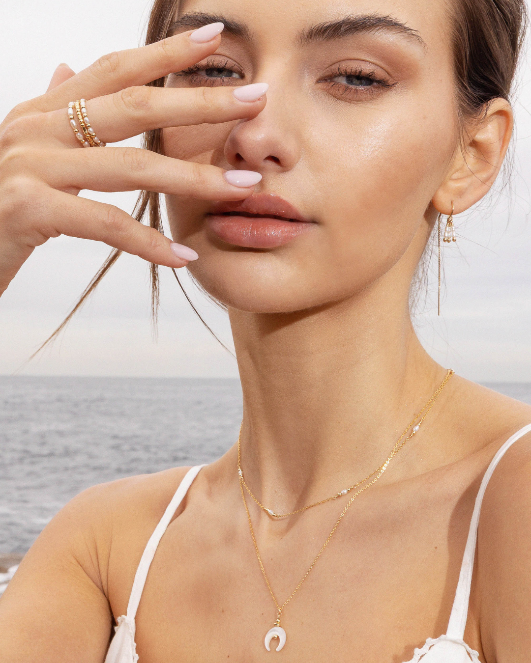 Woman wearing gold jewelry with a blurred beach background
