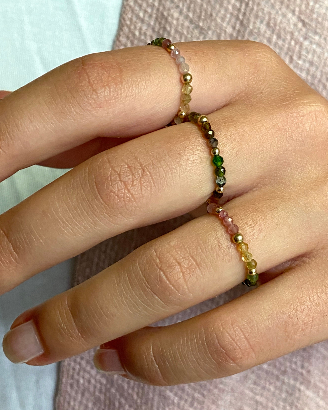 Close-up of a hand wearing a multicolored beaded bracelet on a light background