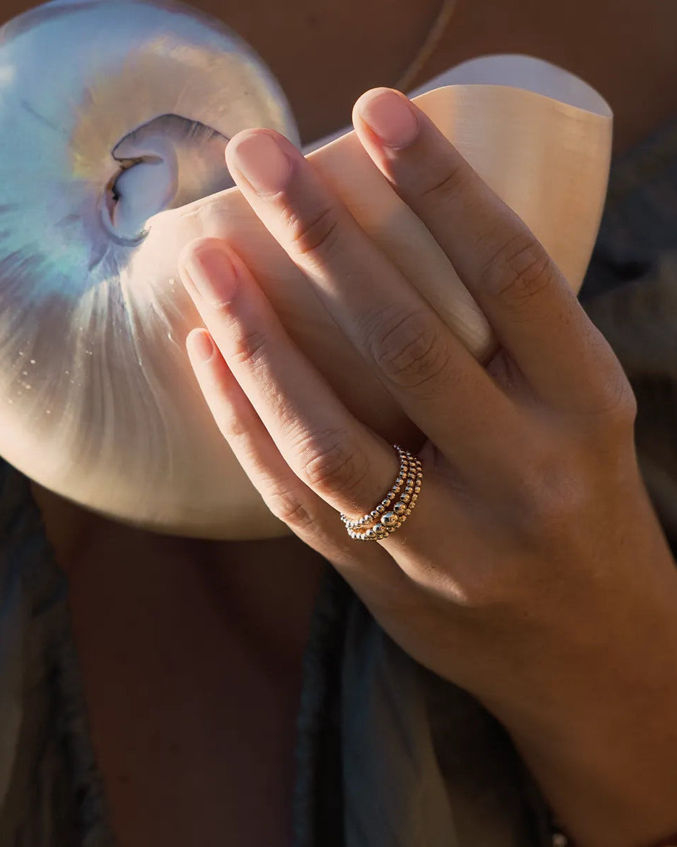 Hand wearing ring featuring a larger centre bead framed by smaller beads