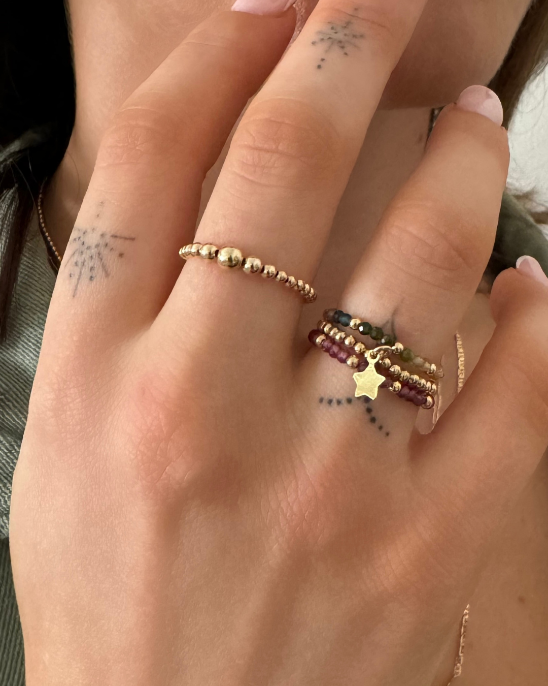 Close-up of a hand wearing multiple gold rings with star designs.