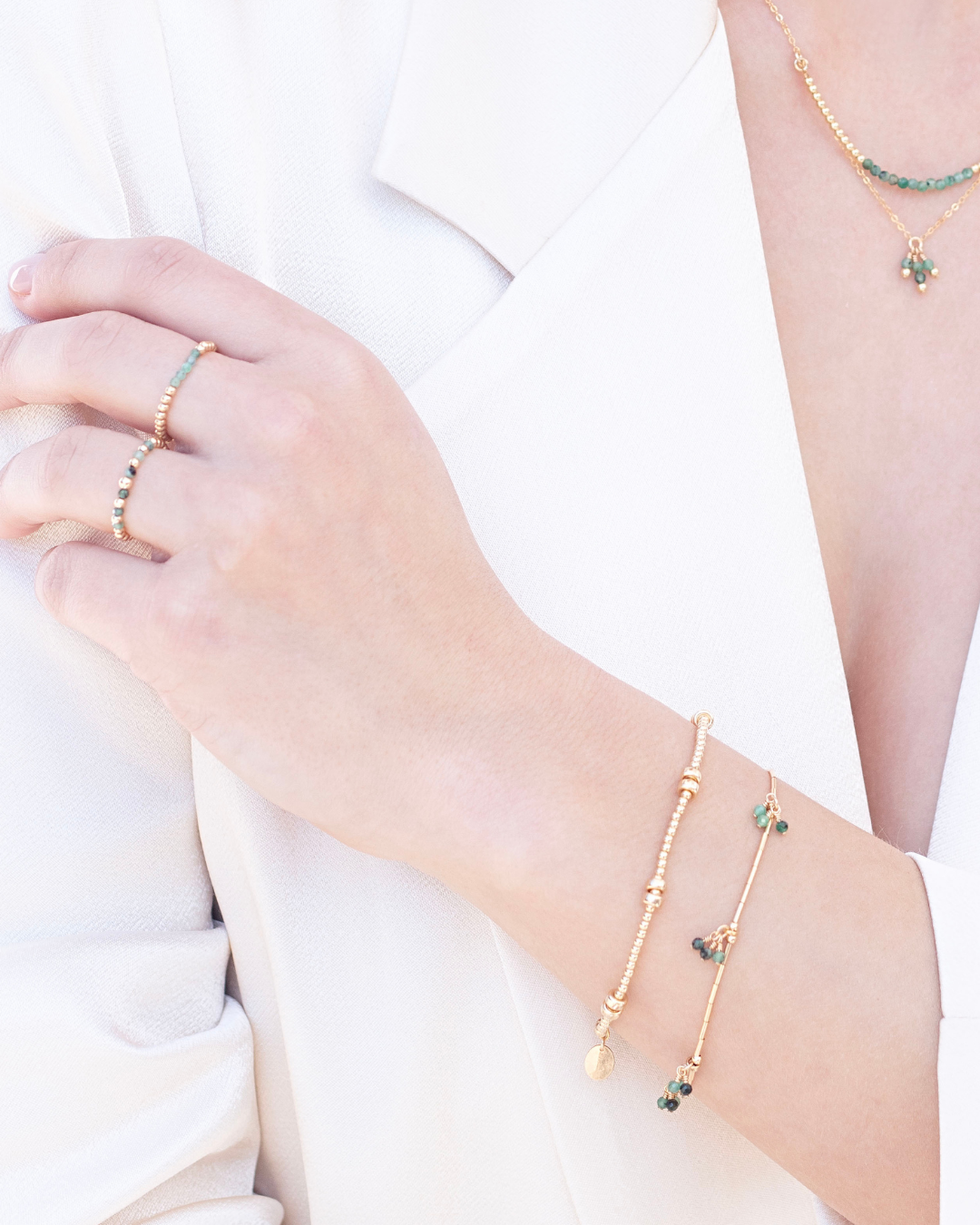 Close-up of a woman wearing bracelets, rings, and a necklace wearing a white jacket