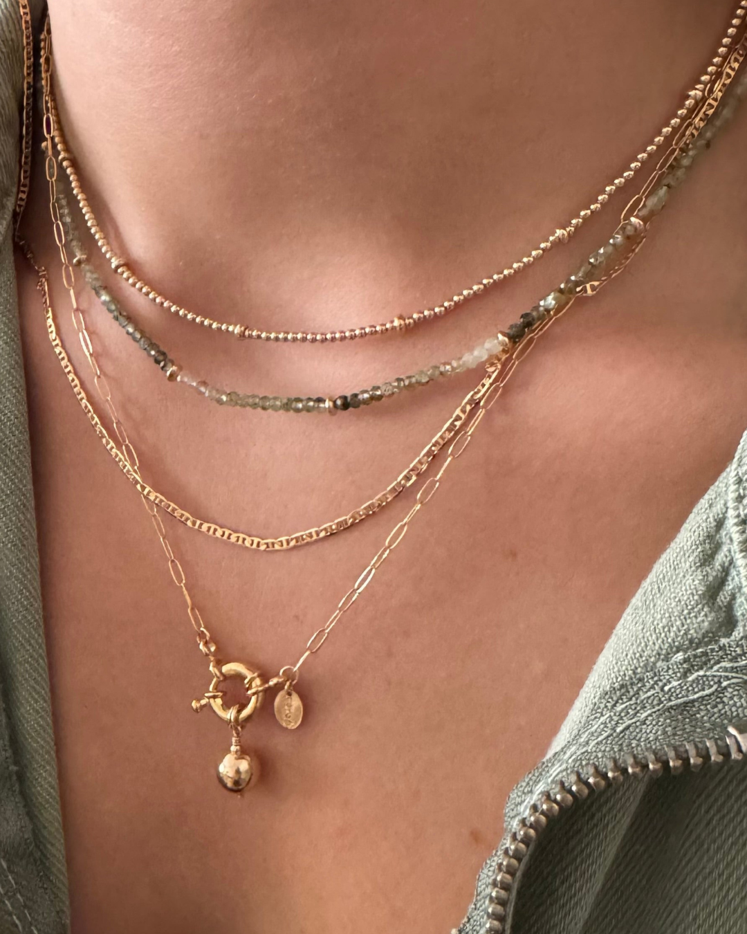 Close-up of a person wearing multiple gold necklaces with a focus on detail.