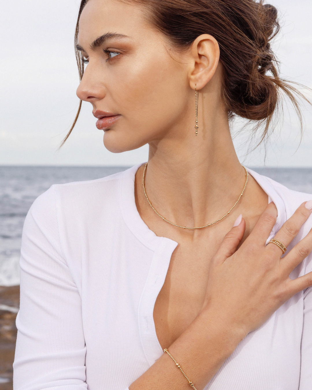 Woman wearing gold jewelry by the sea