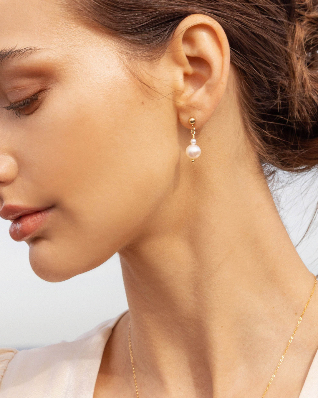 Close-up of a woman wearing pearl earrings with a blurred background