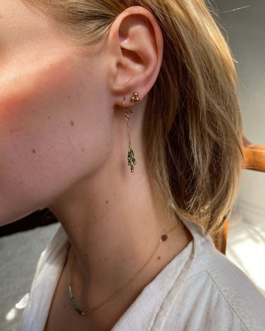Close-up of a person wearing earrings and a necklace with a blurred background