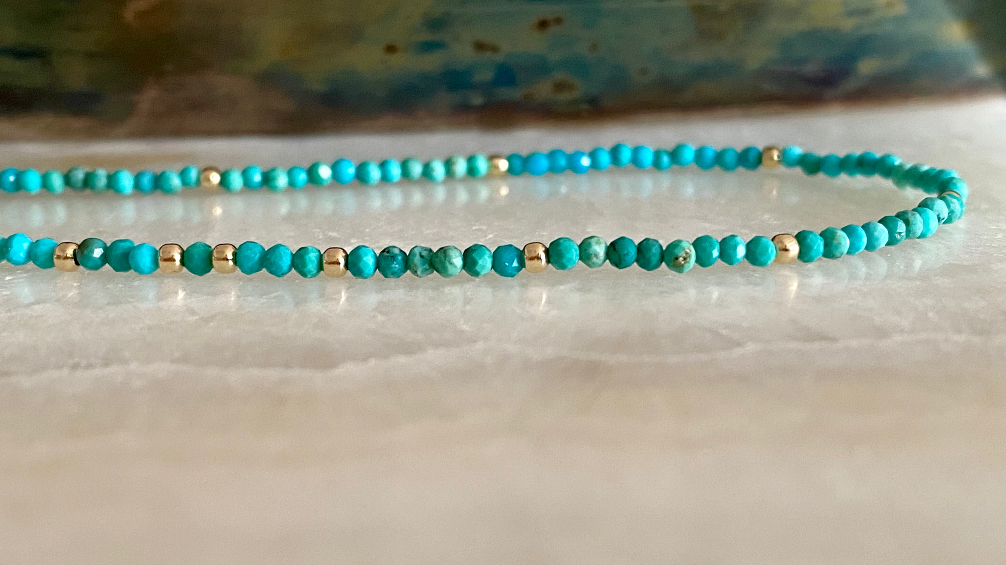 Turquoise beaded necklace on a marble surface with a blurred background