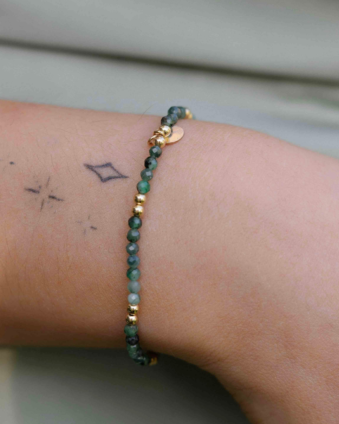 Green beaded bracelet on a wrist with a neutral background
