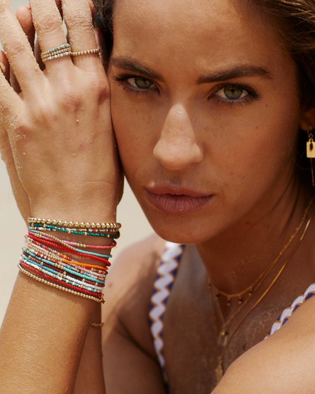 Woman wearing colorful bracelets and rings with a neutral background