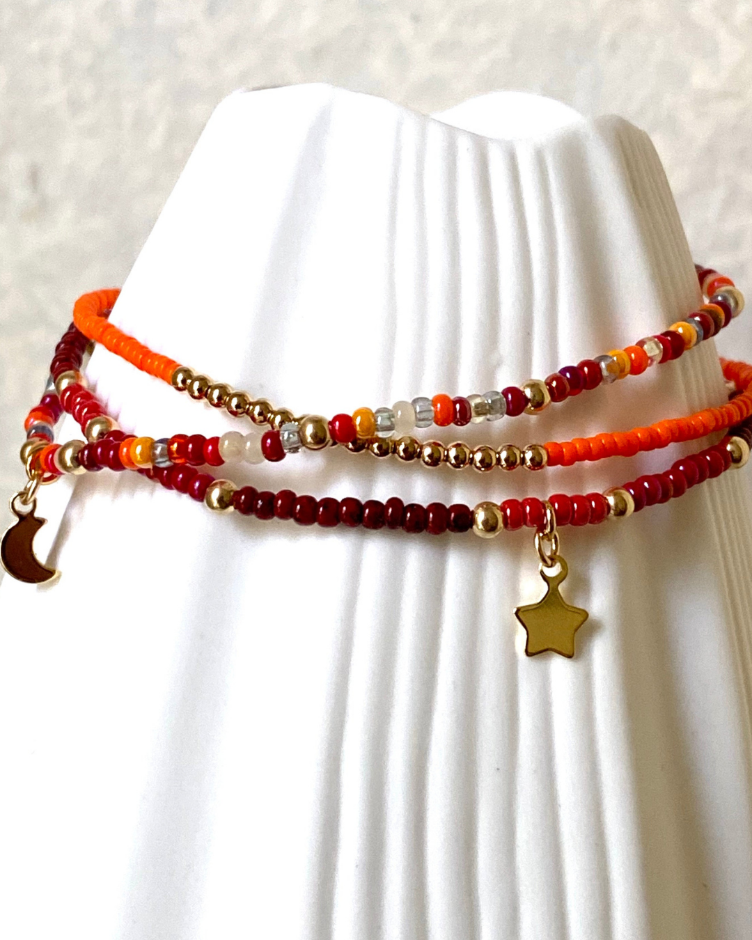 Three beaded bracelets with star and moon charms on a white mannequin.