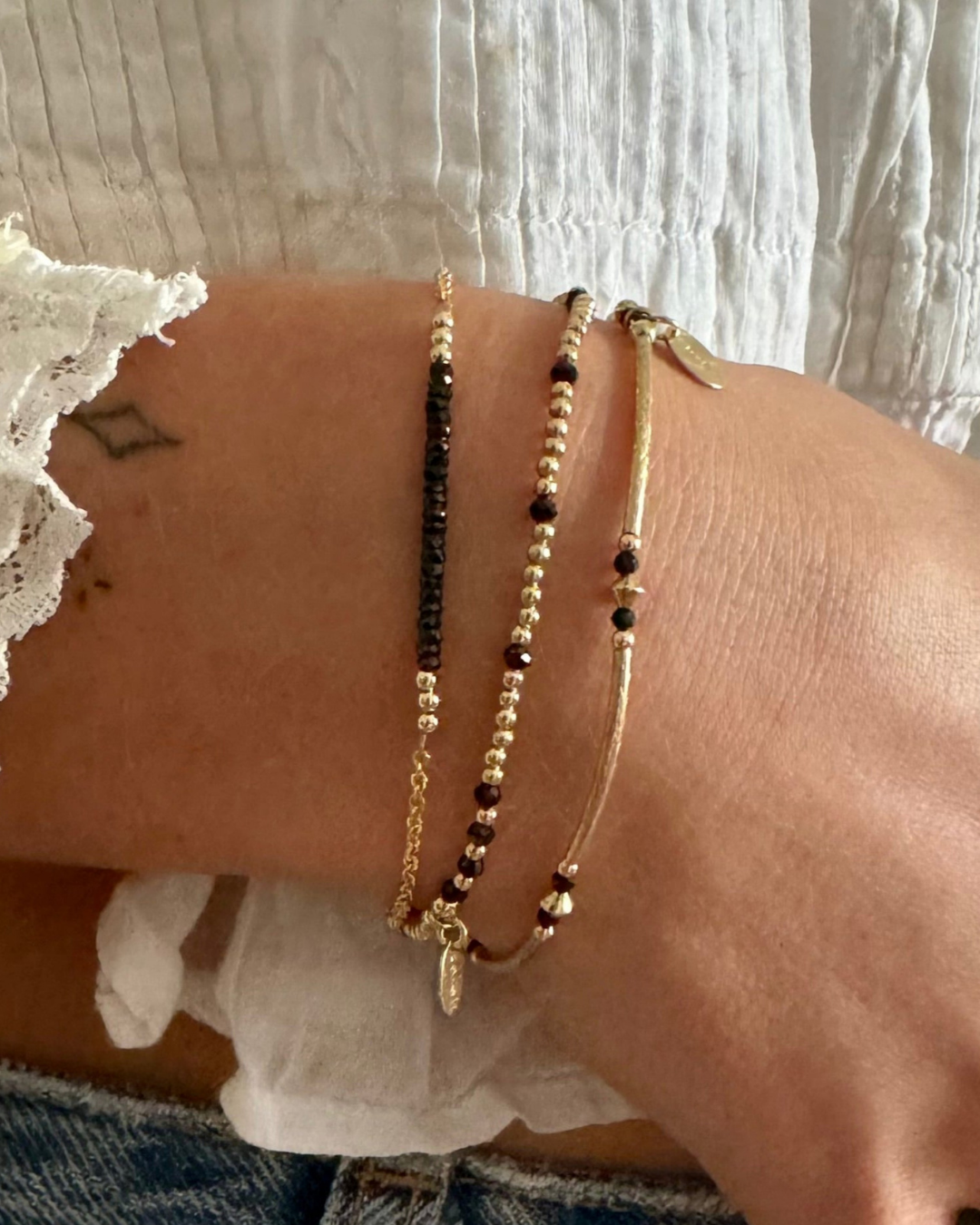 Close-up of a wrist wearing multiple beaded bracelets on a light background