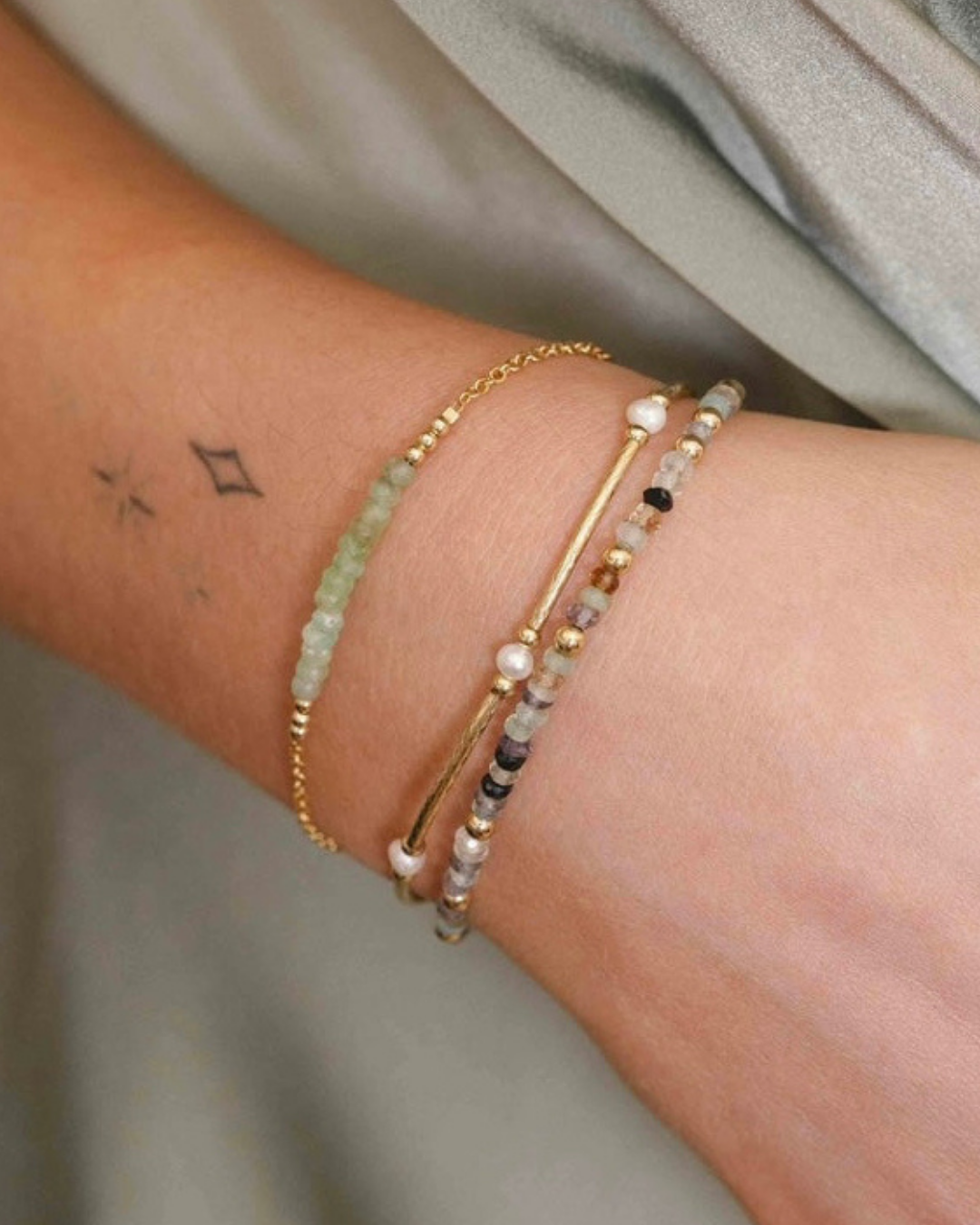 Close-up of a wrist wearing multiple bracelets on a neutral background
