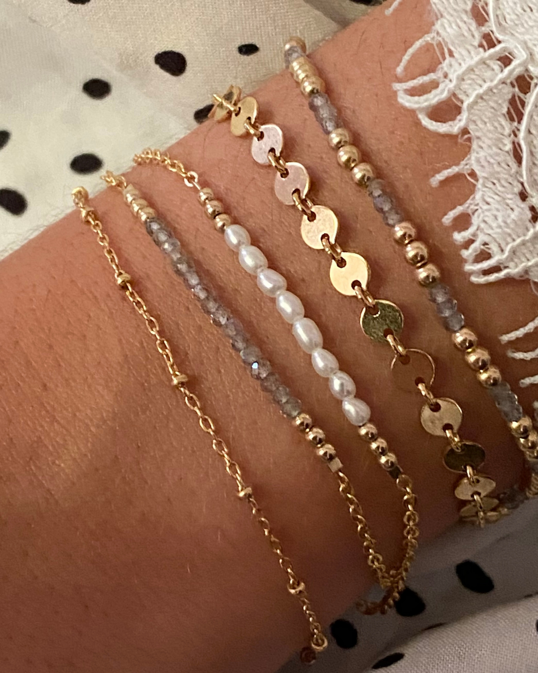 Multiple bracelets on a wrist with a polka dot fabric background