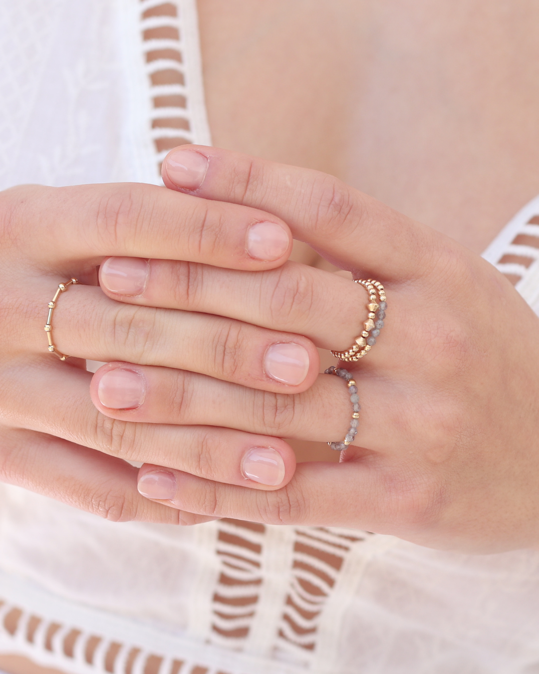 Close-up of hands wearing gold rings and rings with labradorite gemstones with a blurred background