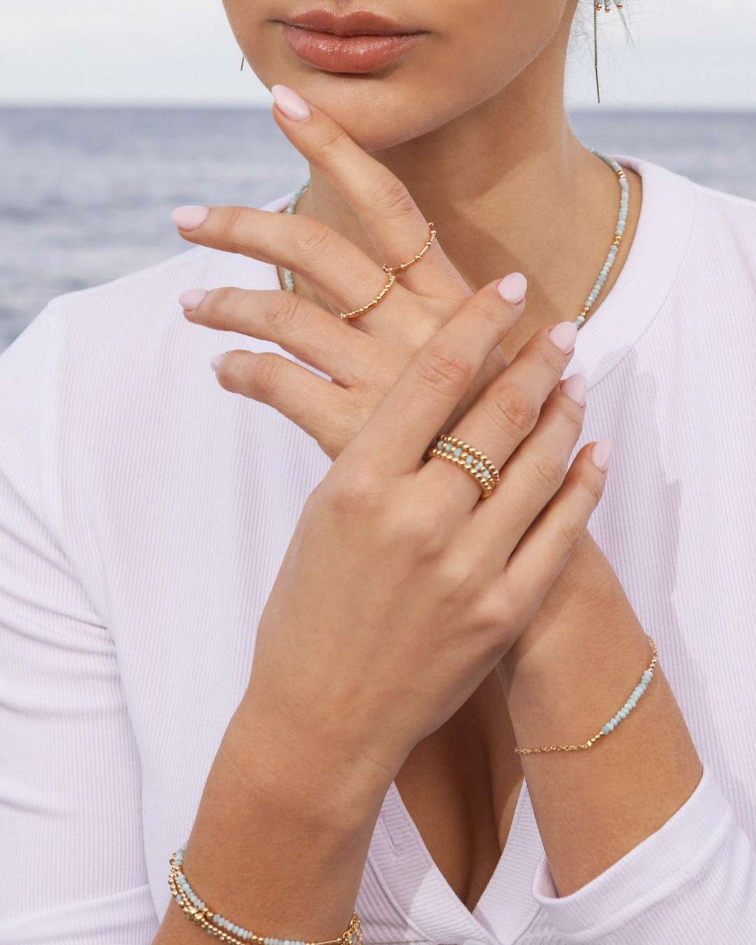 Close-up of a person's hand wearing gold jewelry with a blurred background