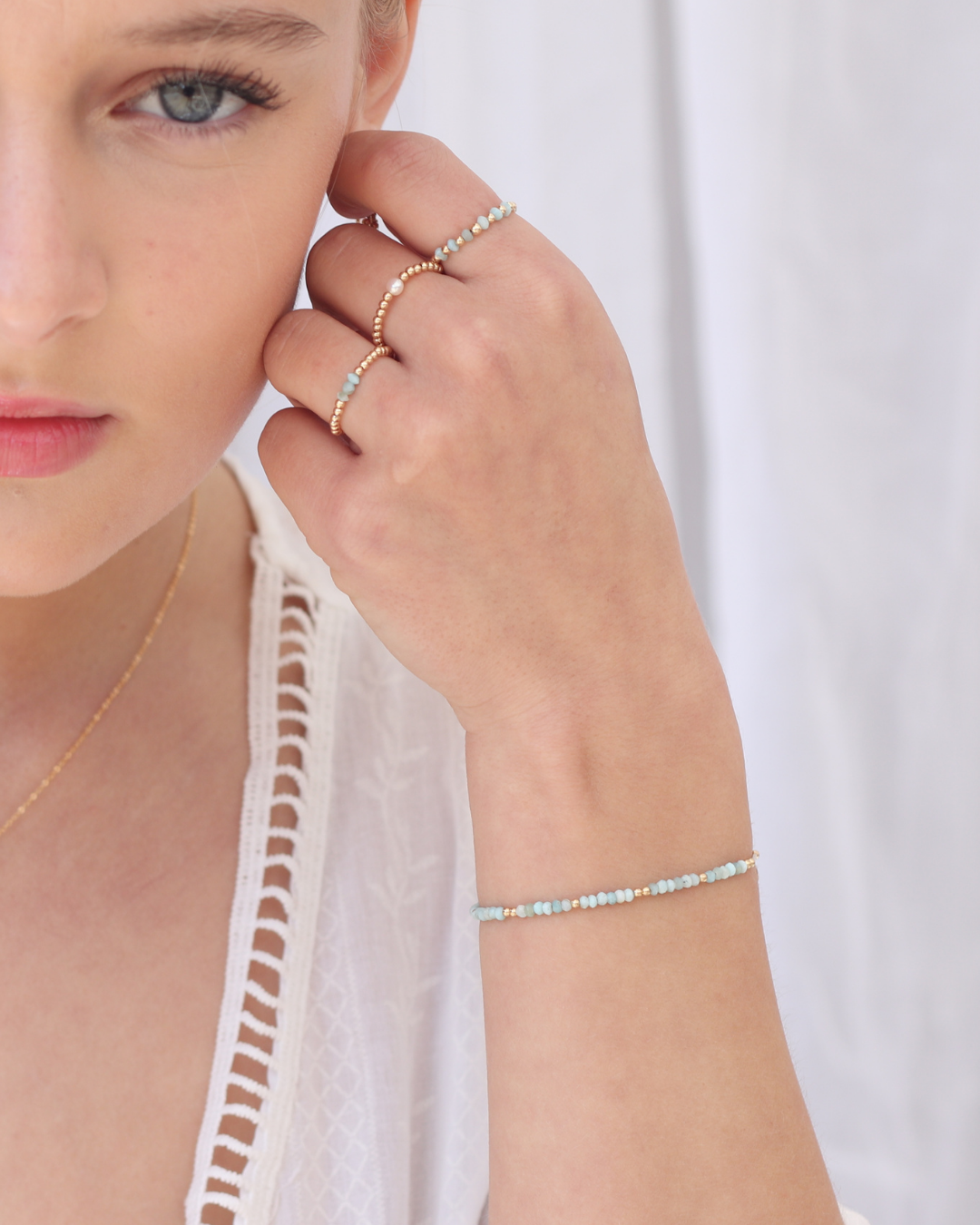Woman wearing multiple pieces of jewellery including larimar gemstone rings and bracelet.