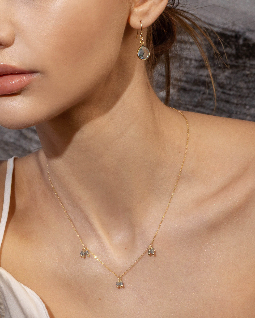 Close-up of a woman wearing a delicate gold necklace with small pendants.