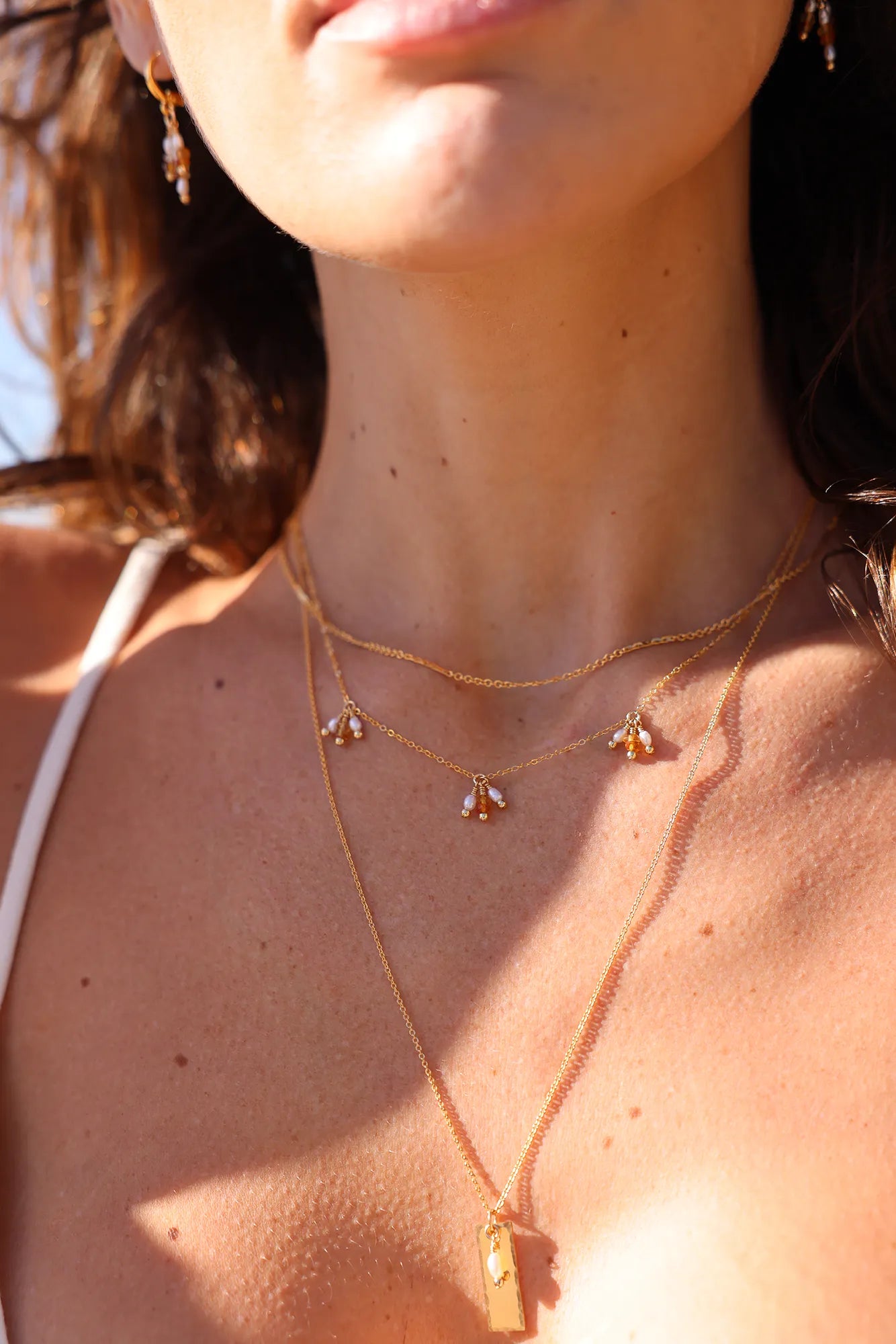 Model wearing gold chain necklace with citrine gemstones and pearl tassels.
