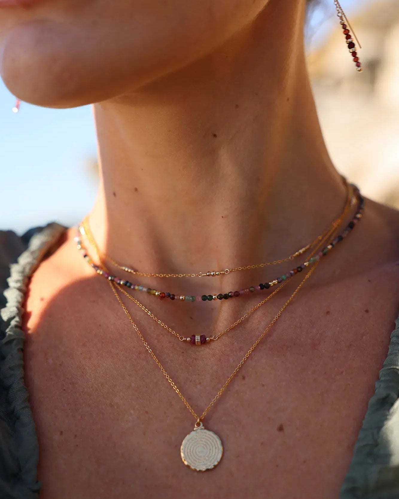 Model wearing gold necklace with a round pendant engraved with 'Our Father ...'