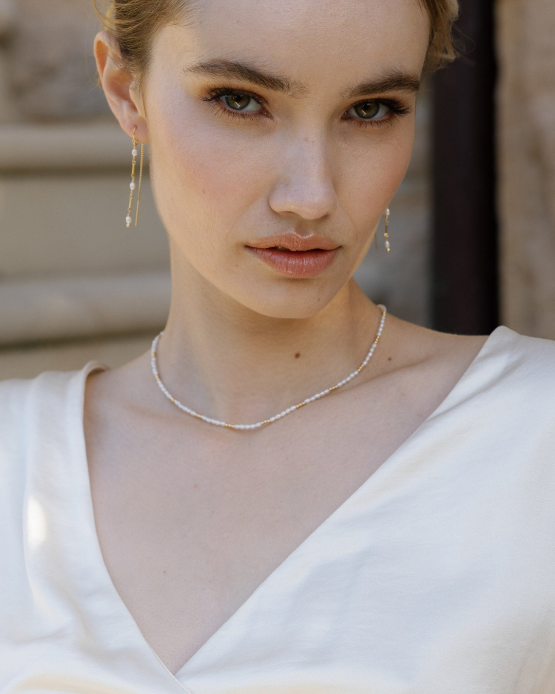 Woman wearing a pearl necklace and earrings with a blurred background