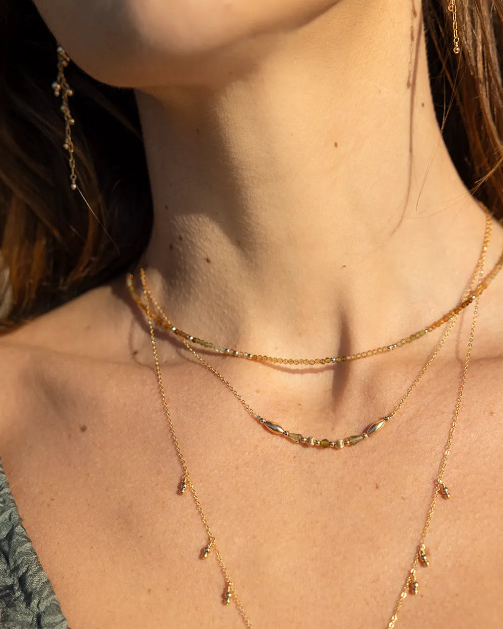 Model wearing gold necklace with green tourmaline gemstones