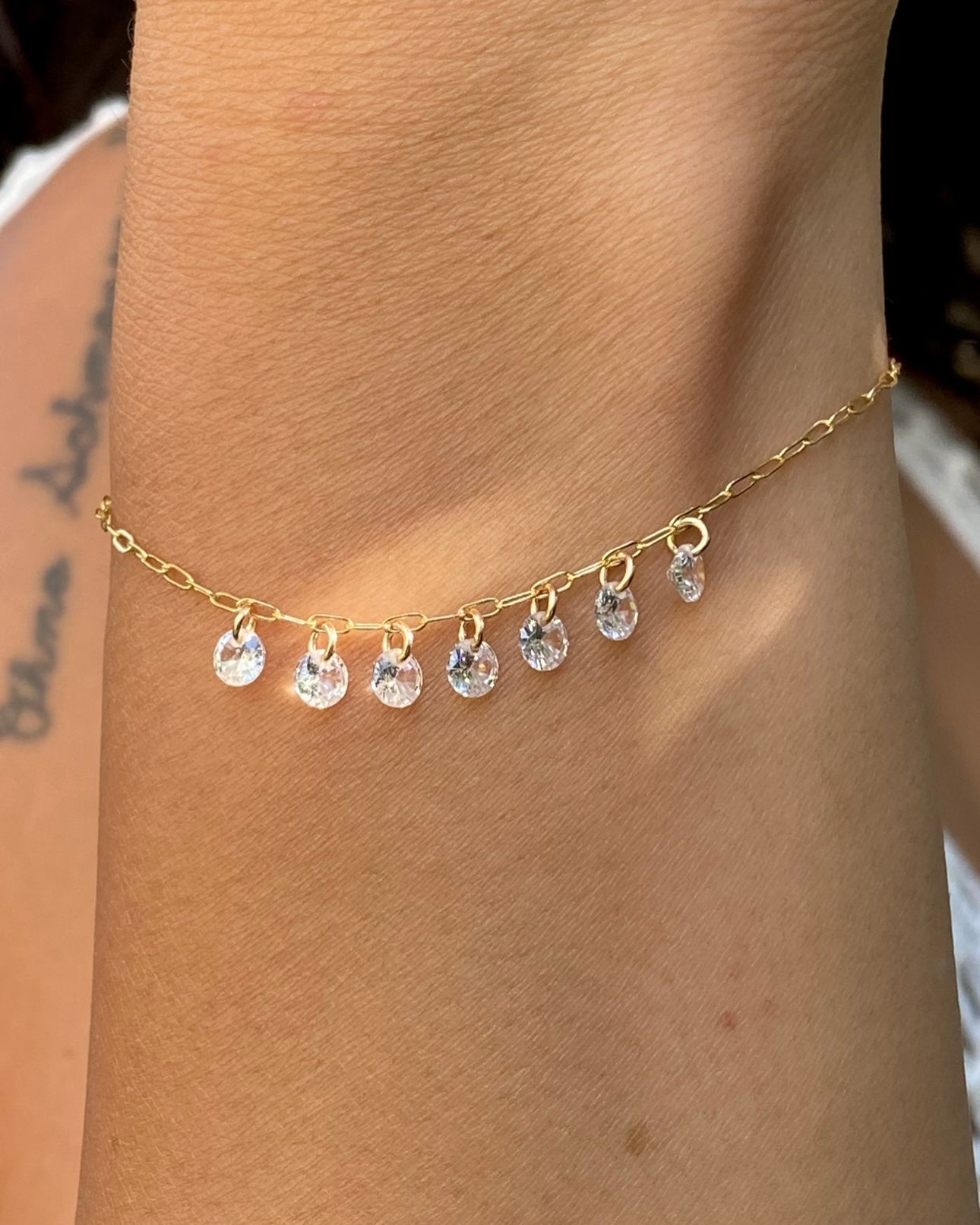 Close up of a woman's wrist wearing a gold bracelet with cubic zirconia gemstones