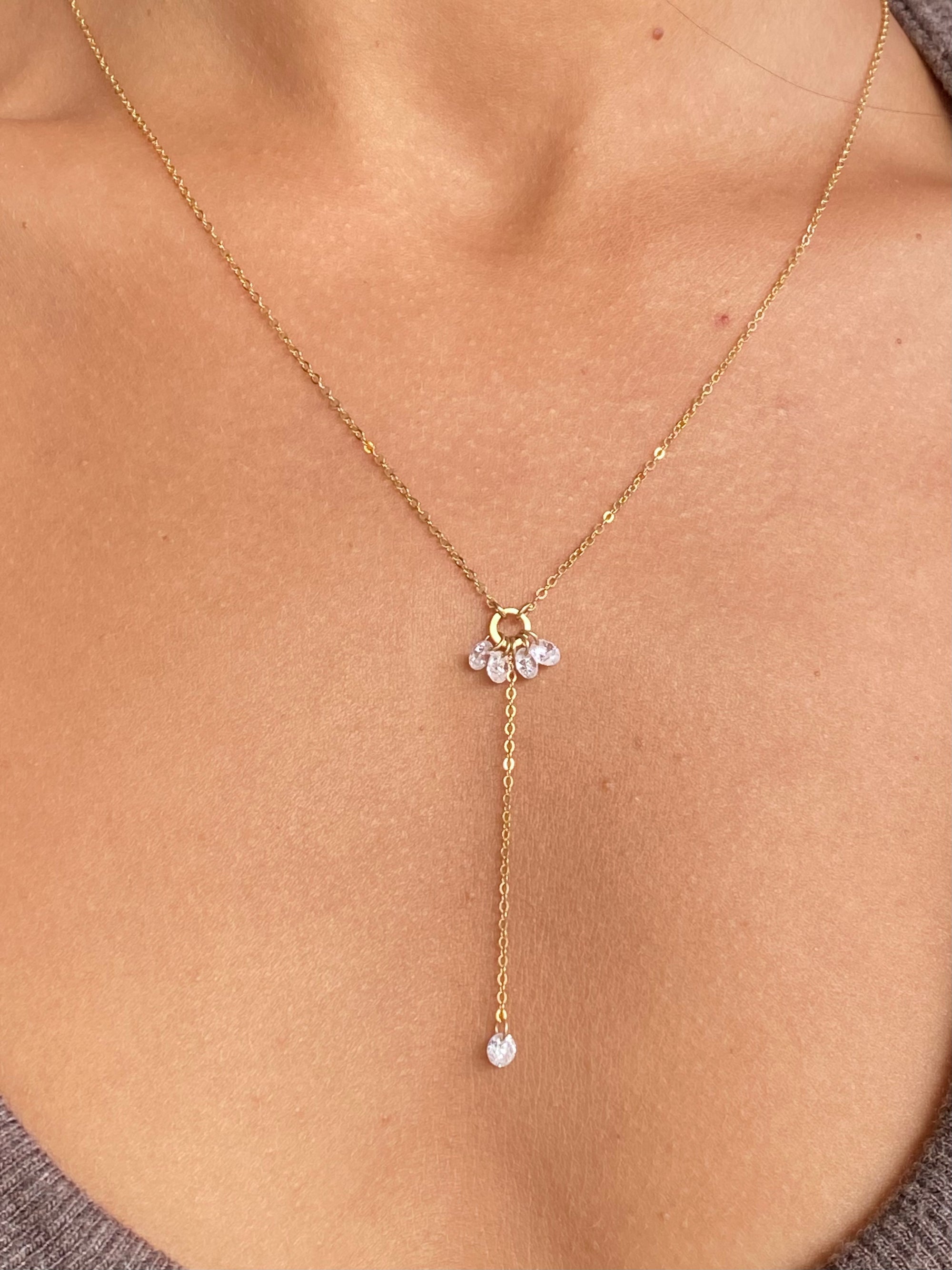 Close up of a woman wearing a gold lariat cubic zirconia necklace