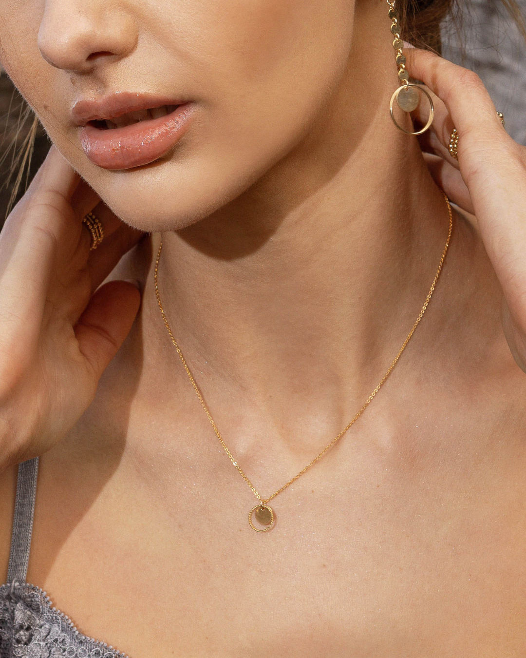 Close-up of a woman wearing gold jewelry including earrings and a necklace.