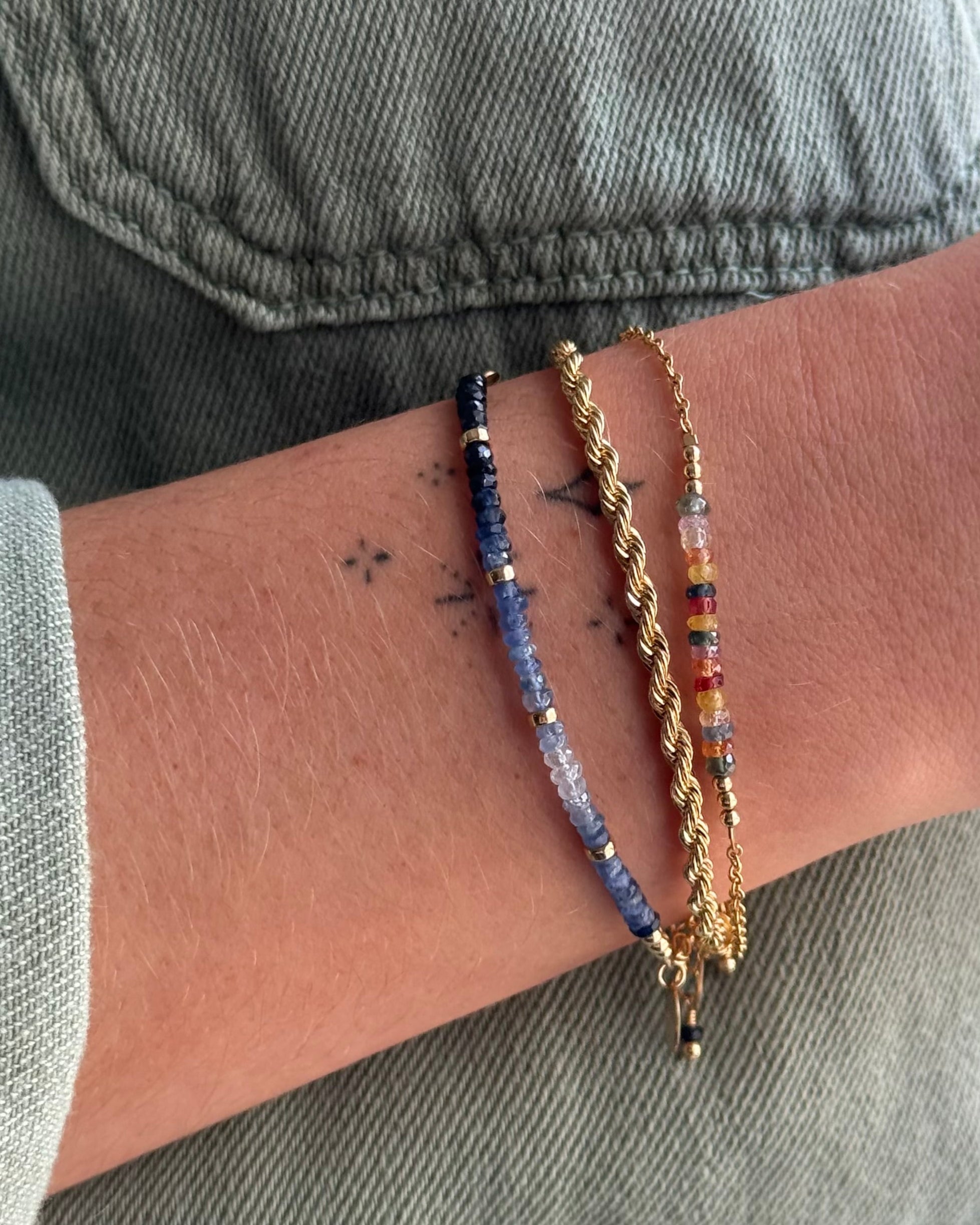 Close-up of a wrist wearing sapphire bracelets with a denim background
