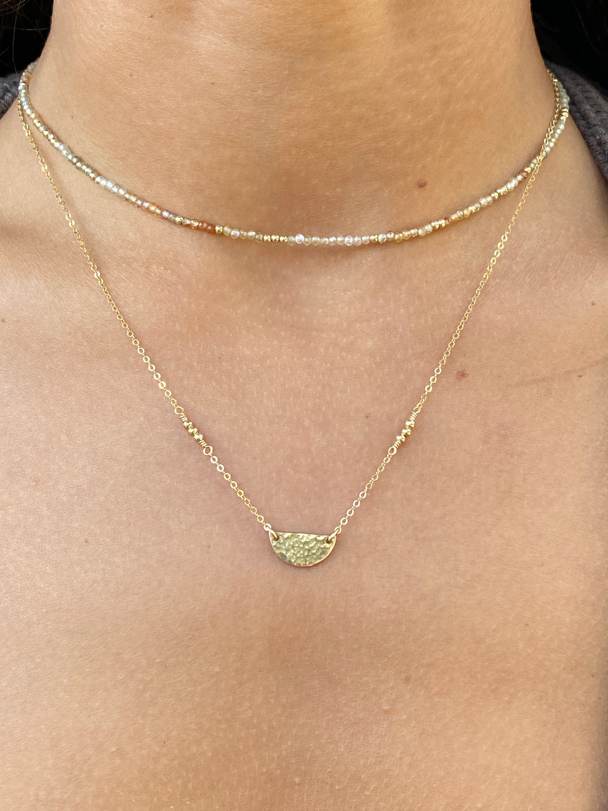 Gold necklace with a pendant on a person's neck
