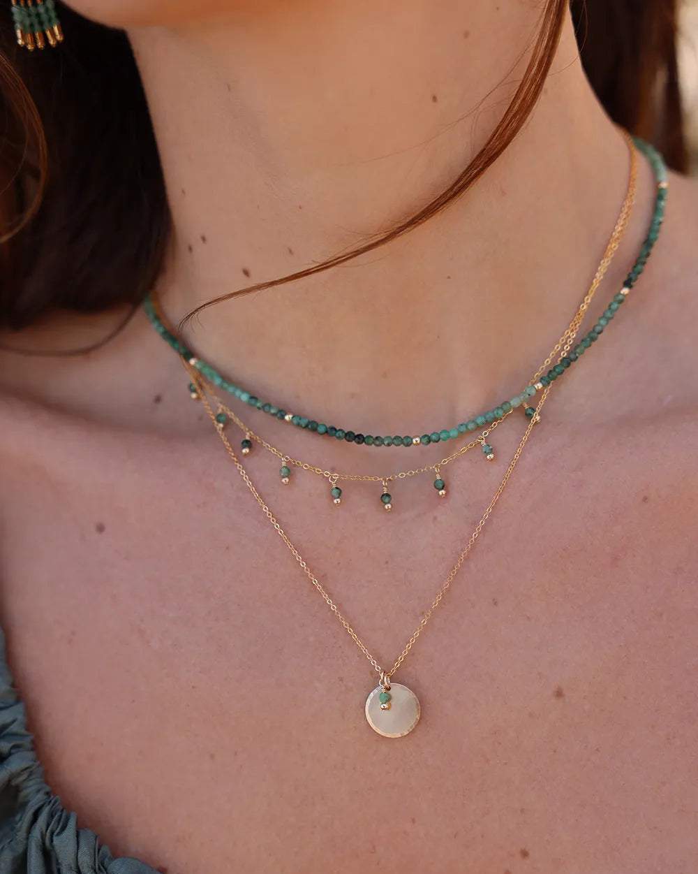 Model wearing necklace with Emerald gemstones and gleaming gold beads, cascading gracefully from a fine gold chain