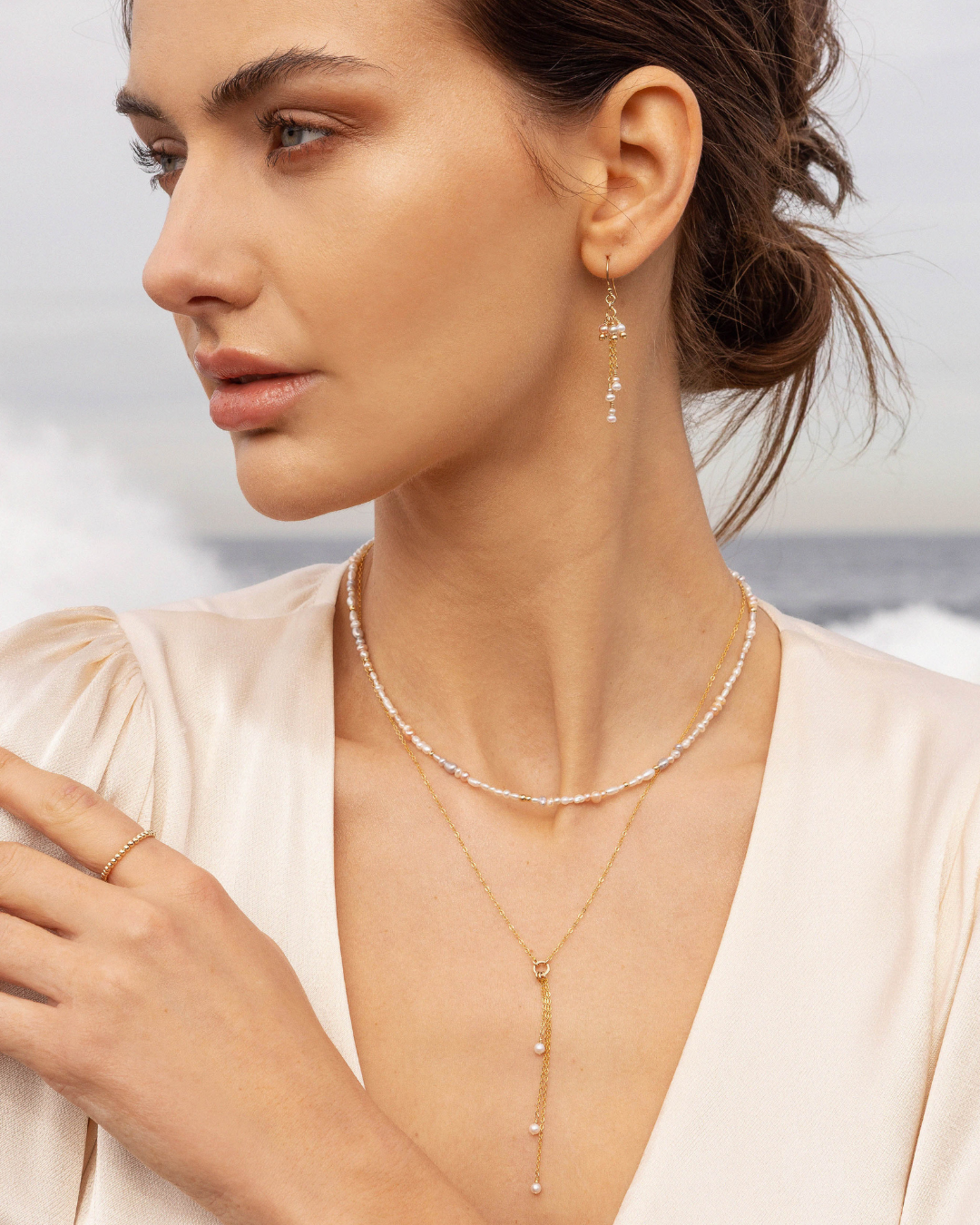 Woman wearing a delicate pearl jewellery  with an ocean background
