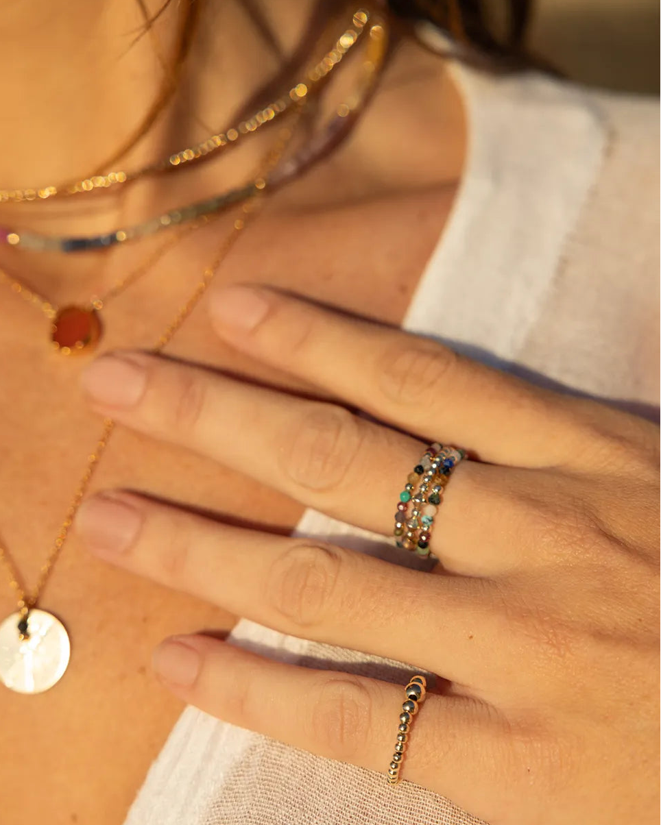 Model wearing stacked rings with multi coloured gems and beads threaded onto durable jewellery stretch cord