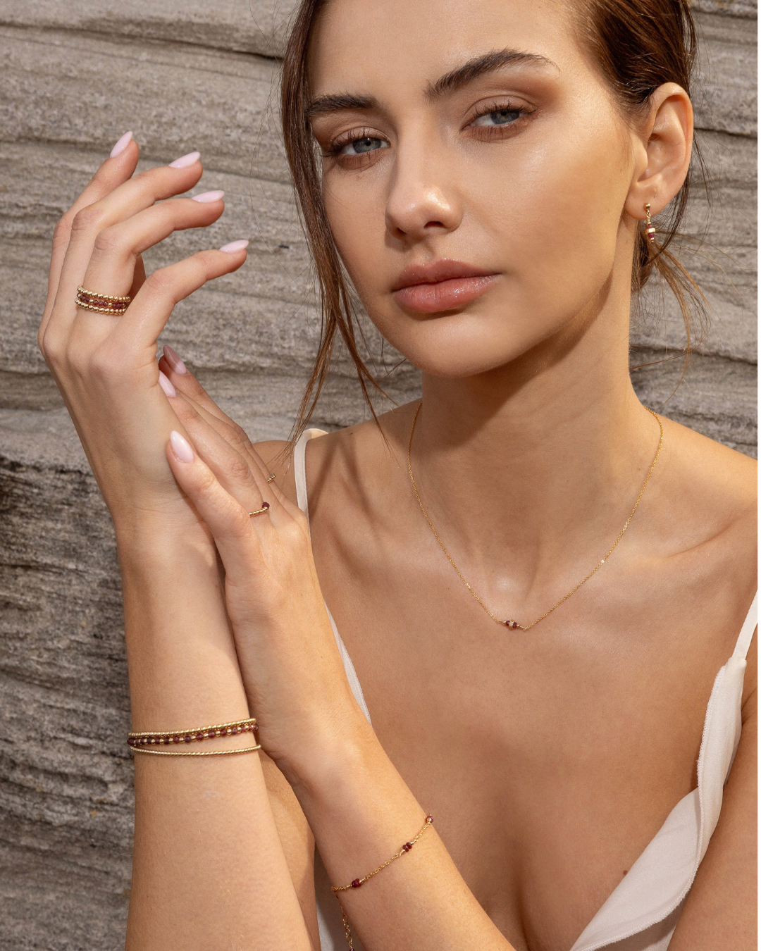 Woman wearing gold jewelry against a wooden background