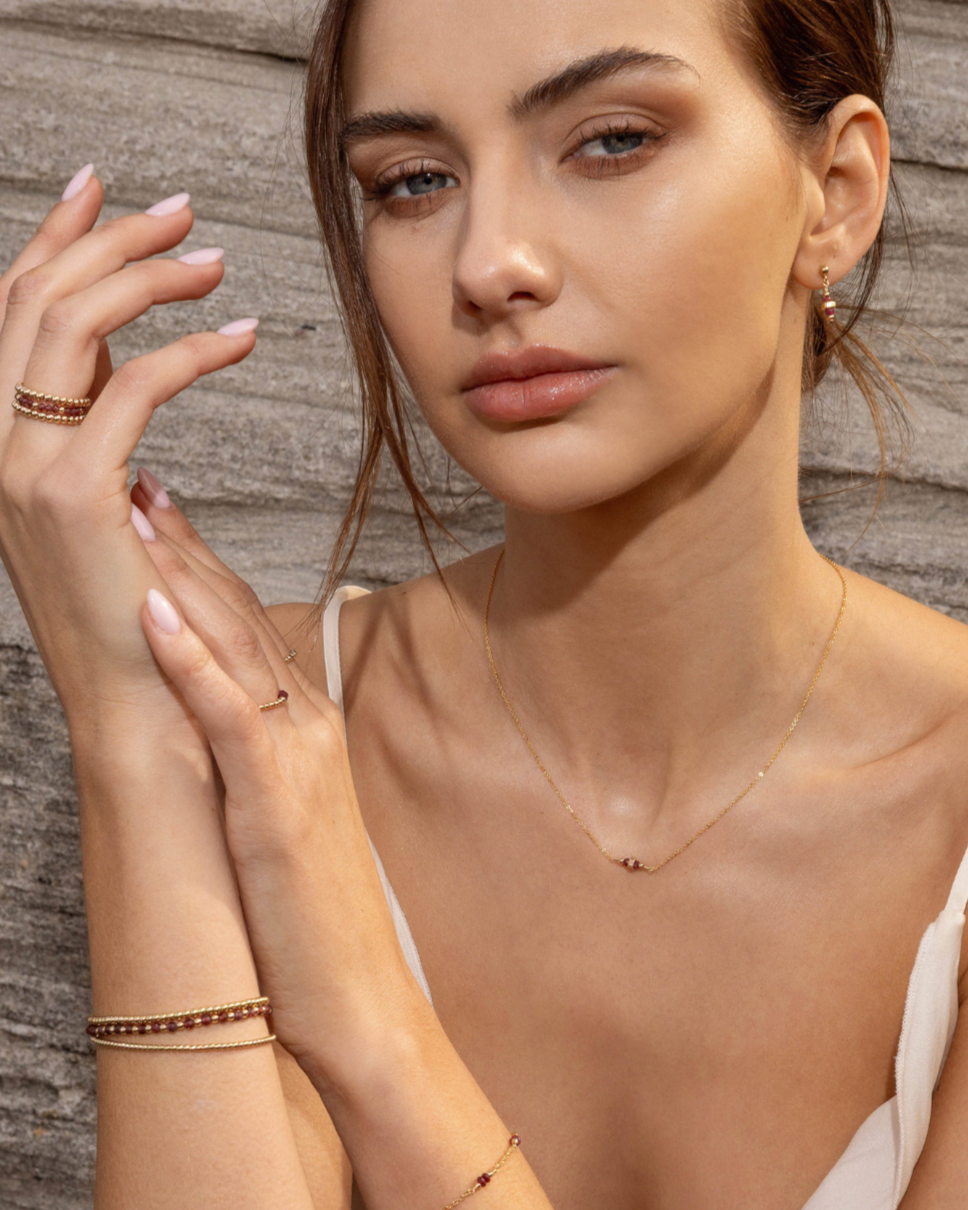 Woman wearing gold jewelry against a wooden background