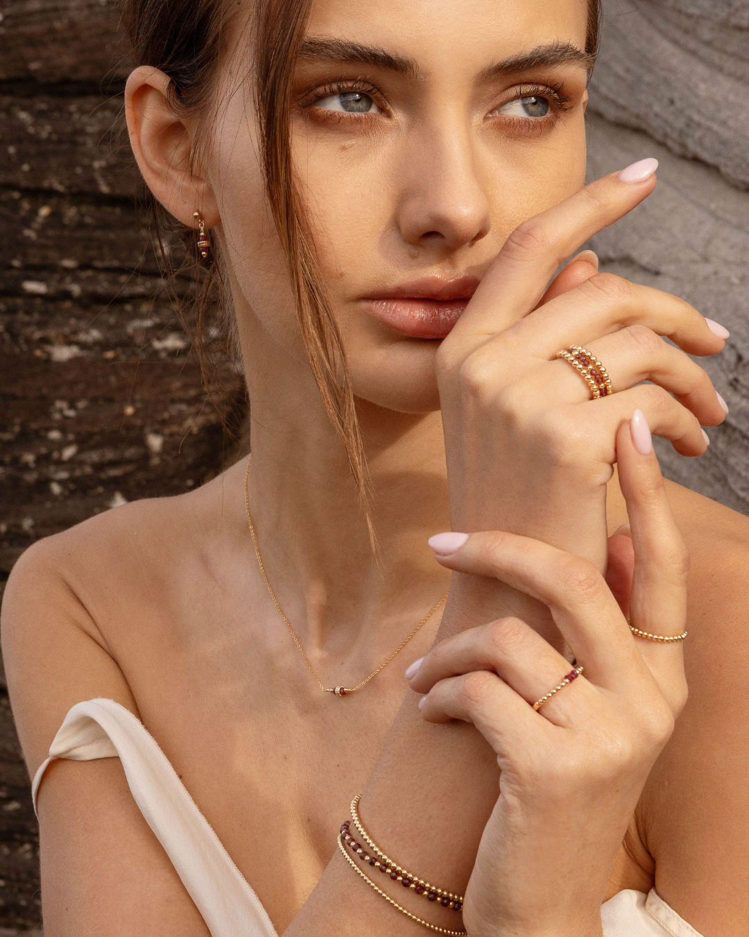 Woman wearing gold jewelry against a rustic background