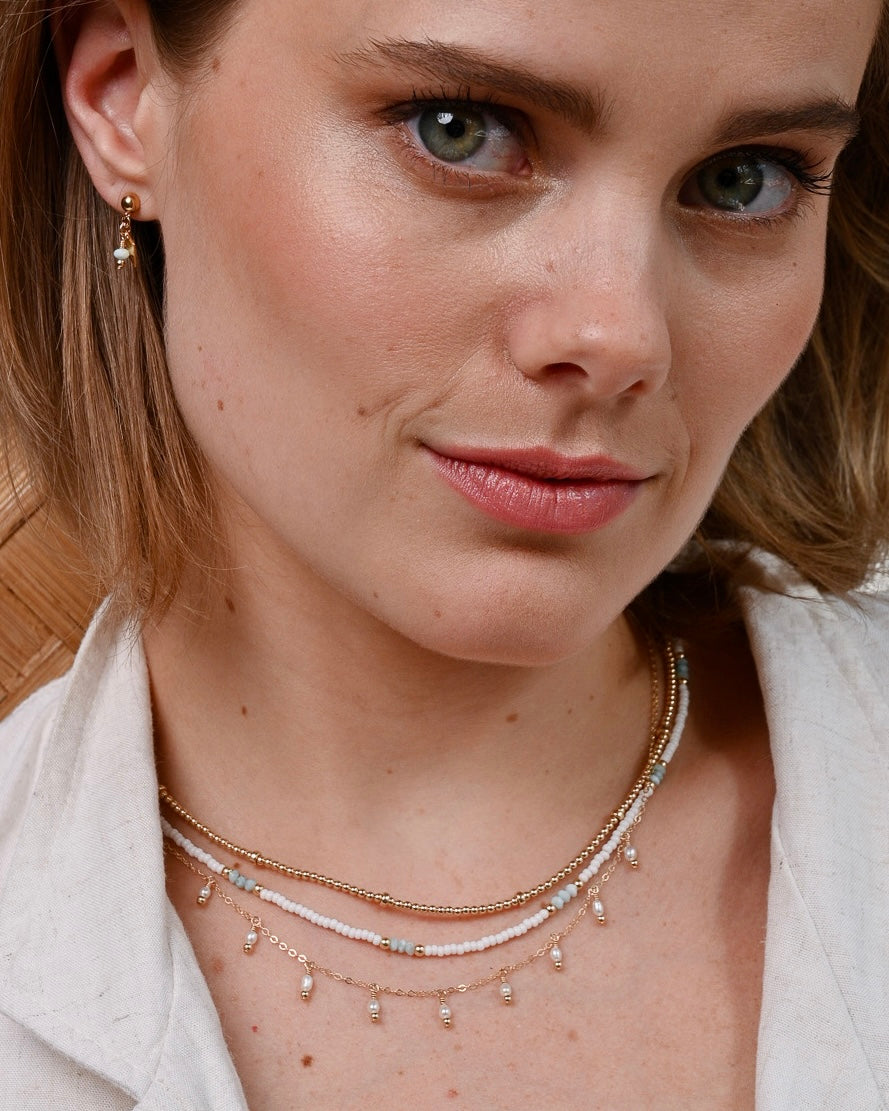 Close-up of a woman wearing gold larimar gemstone jewellery