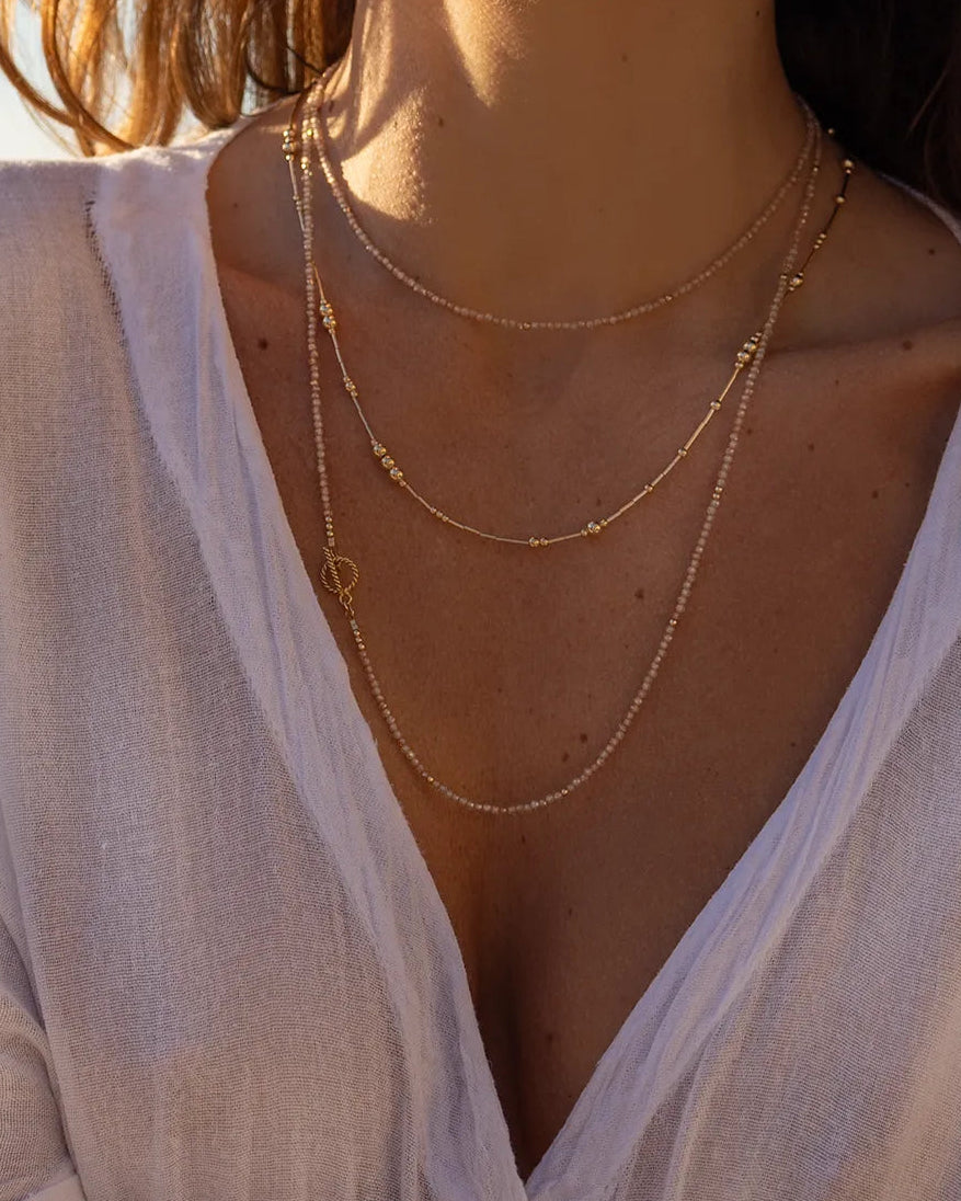 Model waering necklace featuring hundreds of faceted Zircon gems in natural tones, accented with gleaming gold beads, hand-strung onto strong flex wire 