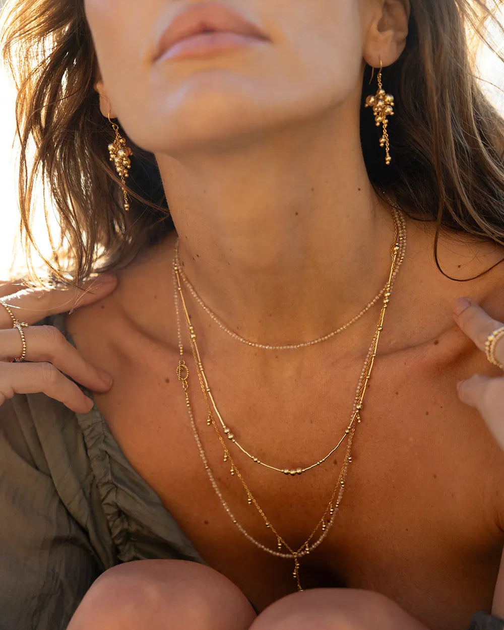 Model waering necklace featuring hundreds of faceted Zircon gems in natural tones, accented with gleaming gold beads, hand-strung onto strong flex wire 