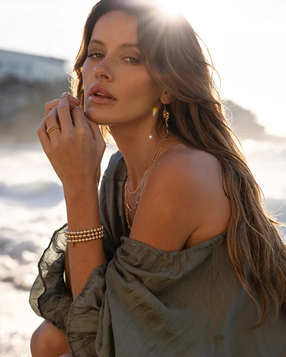 Model wearing bracelets featuring chunky gold beads hand-strung onto durable elastic cord.