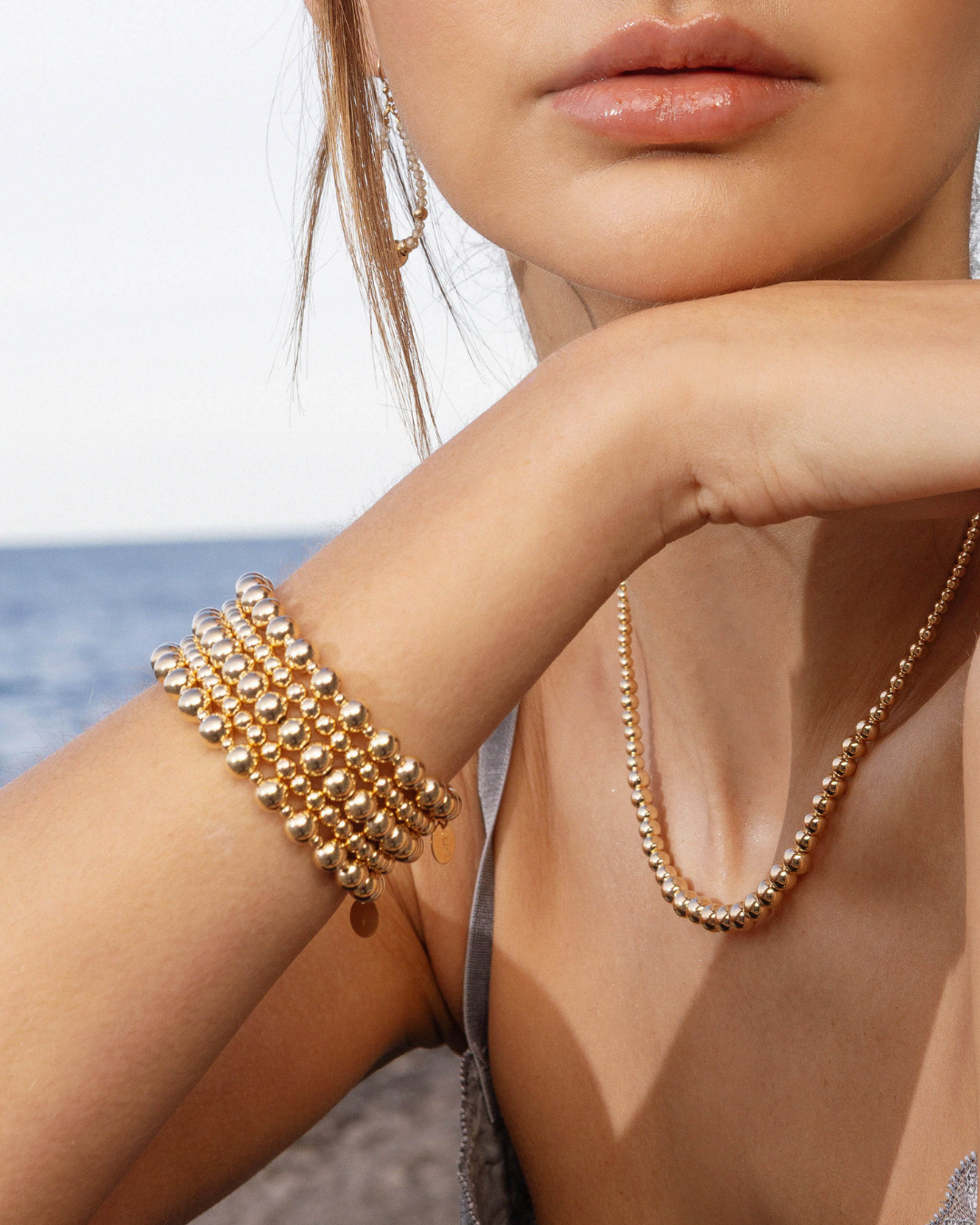 Close-up of a person wearing gold jewelry with a blurred background