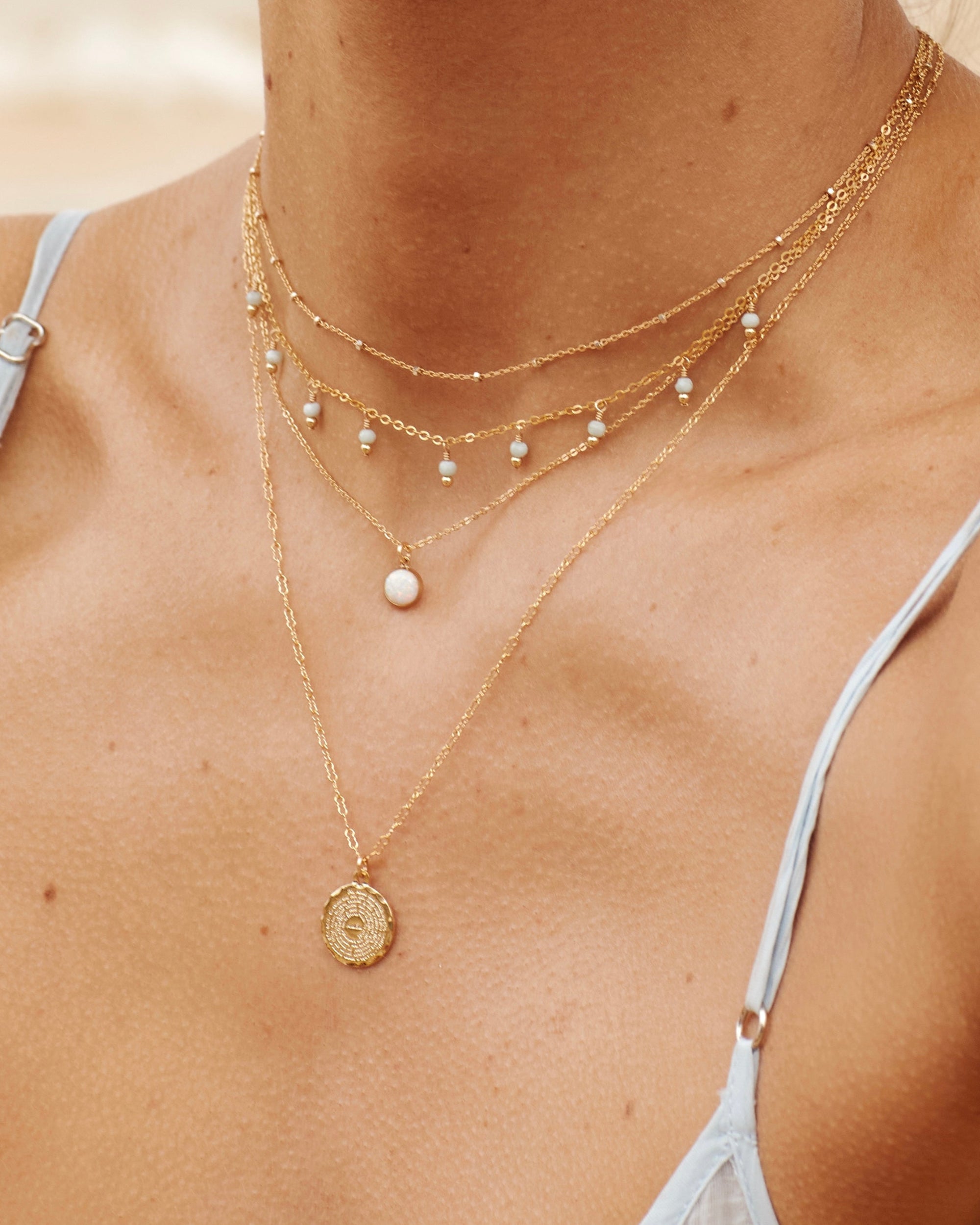Close-up of a person wearing multiple gold necklaces with a blurred background