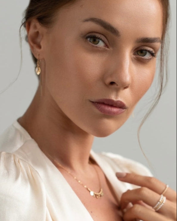 Close-up of a woman wearing gold jewelry against a neutral background