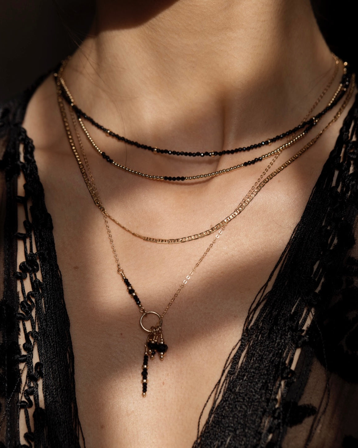 Necklace with black onyx spinel pendant worn by a person against a dark background