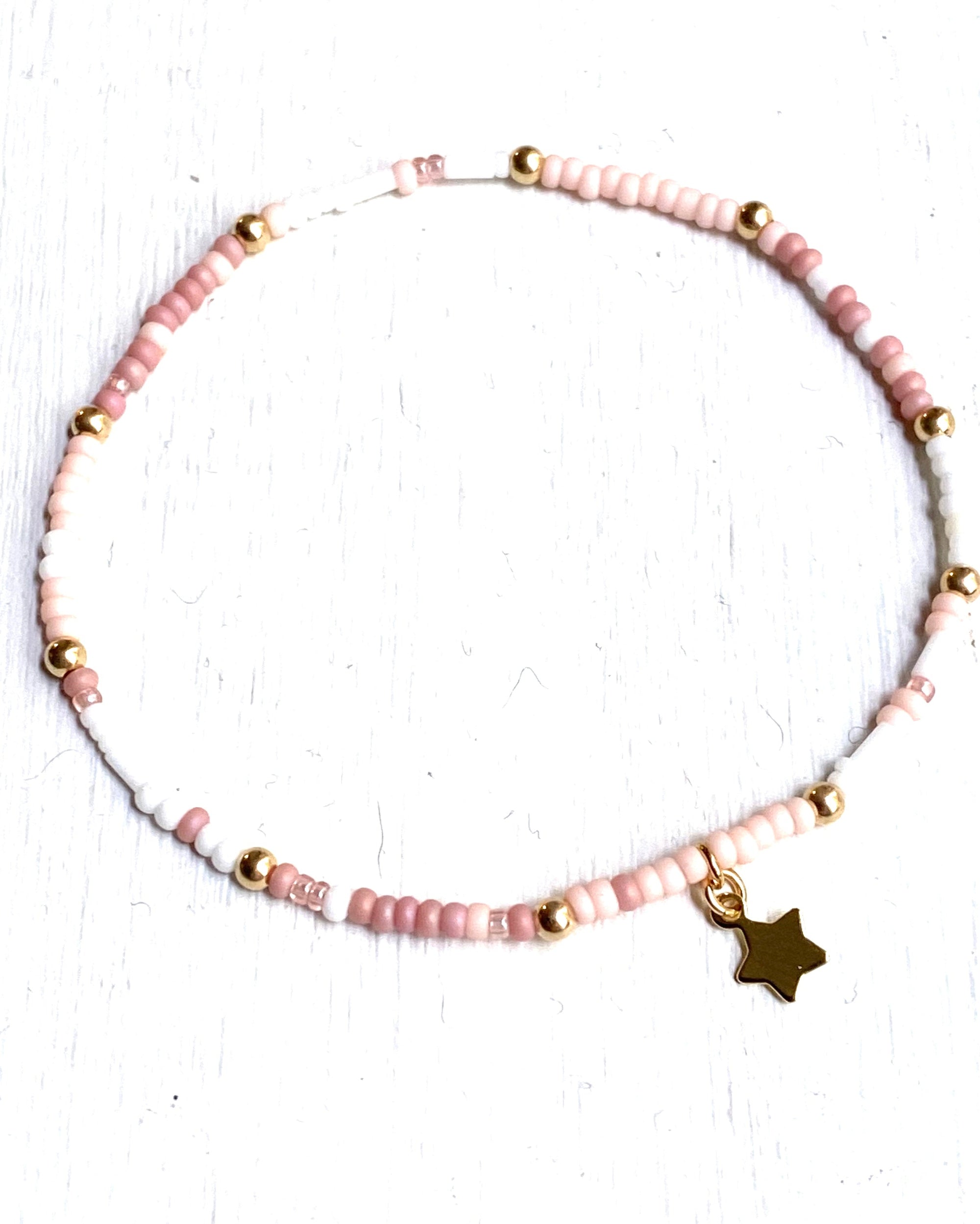 Pink and white and gold beaded bracelet on a white background.