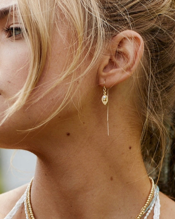 Close-up of a woman wearing gold earrings with a blurred background