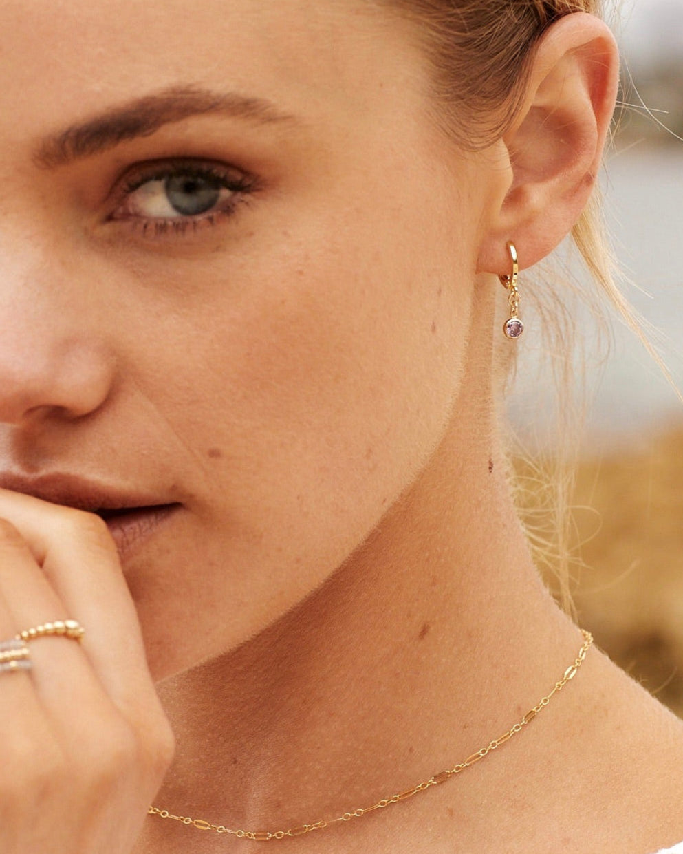 Close-up of a woman wearing gold earrings and a necklace with a blurred background